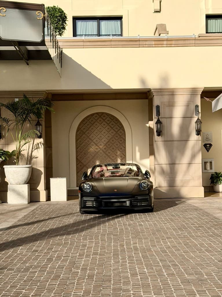 Porsche 911 Turbo S Cabriolet — matte black front view at hotel valet, golden hour